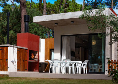 Galería semicubierta de Casa Moby Dick en Mar Azul con parrilla, mesa de exterior y vista al bosque.