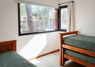 Segundo dormitorio de Casa Moby Dick en Mar Azul con camas individuales y vista al bosque a través del ventanal.