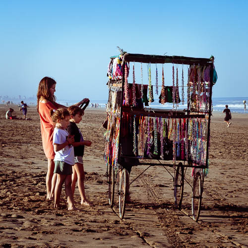 Turistas visitando un puesto de artesanías en la playa de Mar Azul, Buenos Aires
